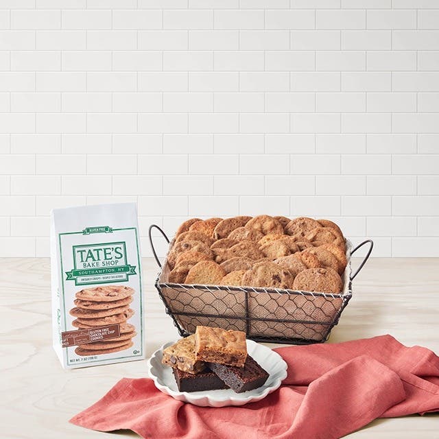 An open tin of cookies, bag of cookies and plate of dessert bars on a table